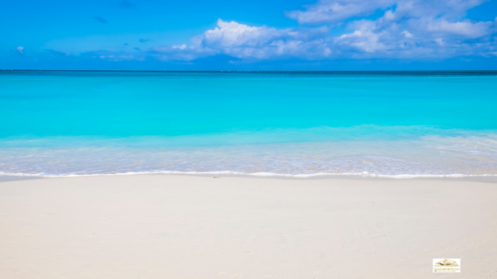 Best family island vacations: Leeward Beach in Turks and Caicos with soft white sand, calm clear turquoise water, and a wide open shoreline under a sunny sky.