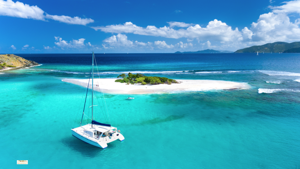 Best family island vacations: a catamaran anchored off Sandy Spit in the Virgin Islands beside a white sand beach and clear turquoise water.