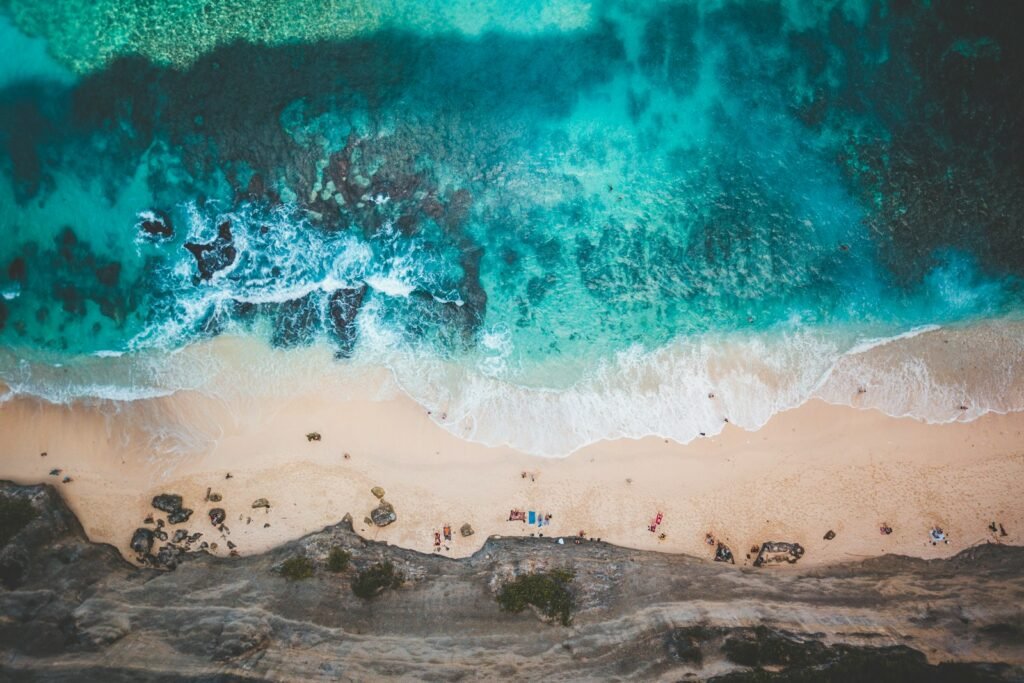 Aerial view of people relaxing on a sunny Bali beach during the day, a tropical pick for best honeymoon destinations.