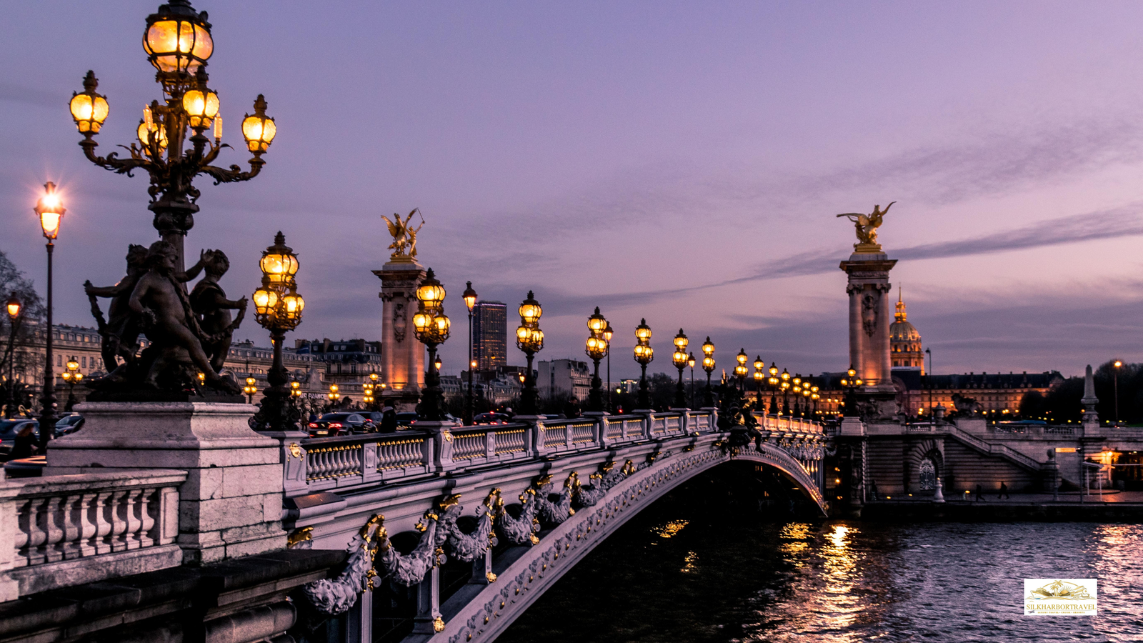 Luxury hotel in Paris France night scene with an old bridge over the river and warm city lights reflecting on the water