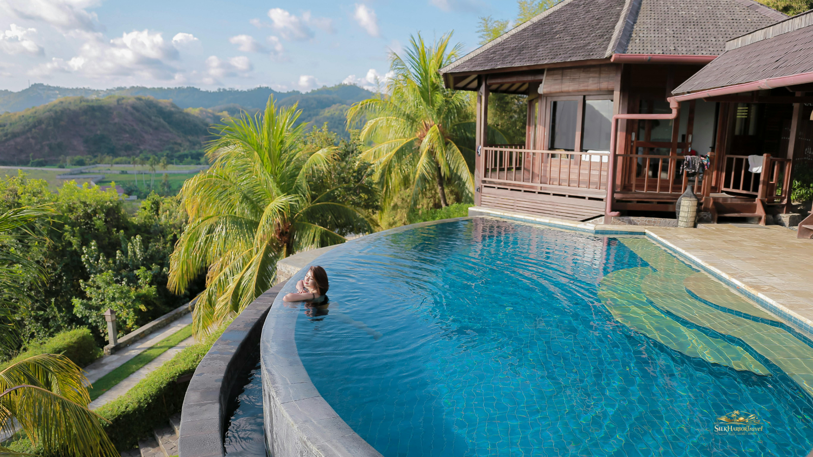 Woman in an infinity pool with forest and mountain views, capturing luxury in Bali