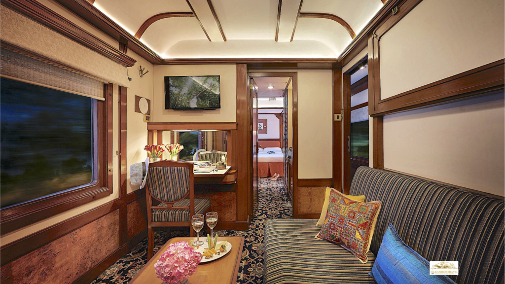 Luxury train trips suite bedroom with a large window, sofa, and champagne glasses on a table