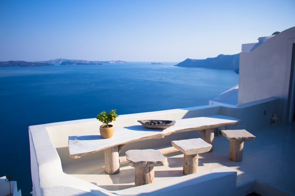Bench and dining table beside calm water under a soft sky on a Greek island, romantic setting for best honeymoon destinations.