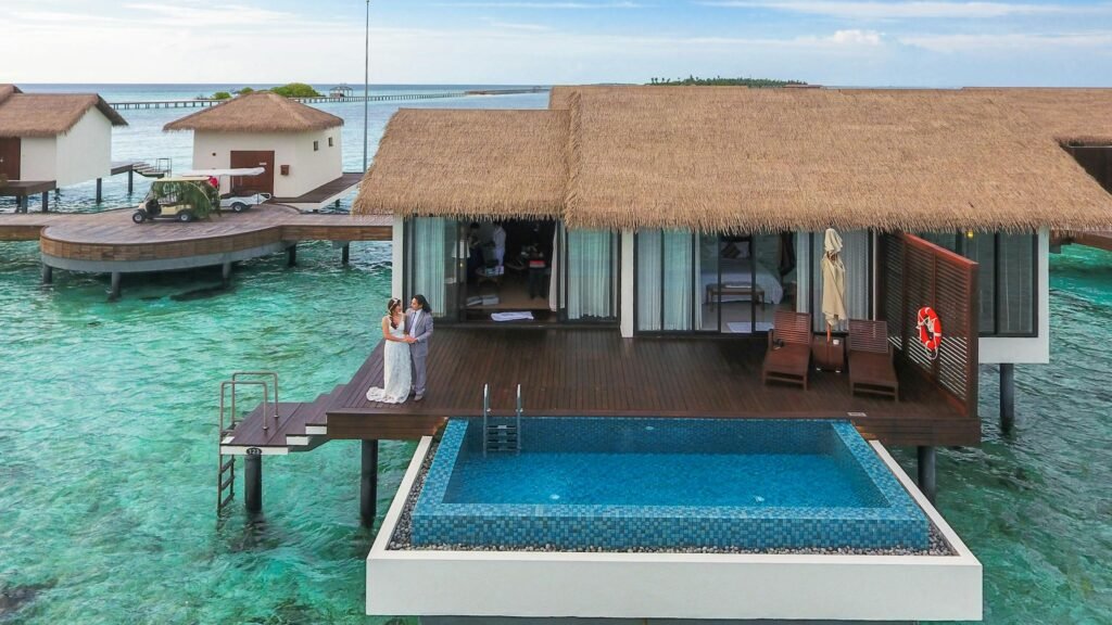 Couple on an overwater villa deck with an infinity pool, representing the best luxury resorts for honeymoons