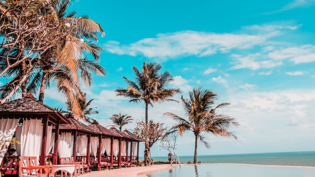 Featured image for best luxury resort amenities showing a tropical infinity pool, cabanas, and palm trees beside the sea.