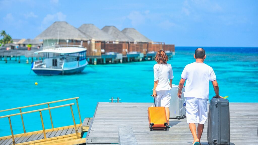 A couple arriving at a luxurious Maldives resort dock with luggage, tropical waters in the background.