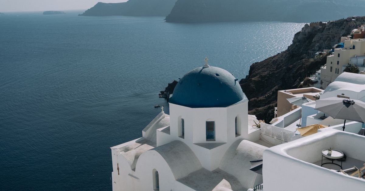 Whitewashed buildings and blue domes above a cliff