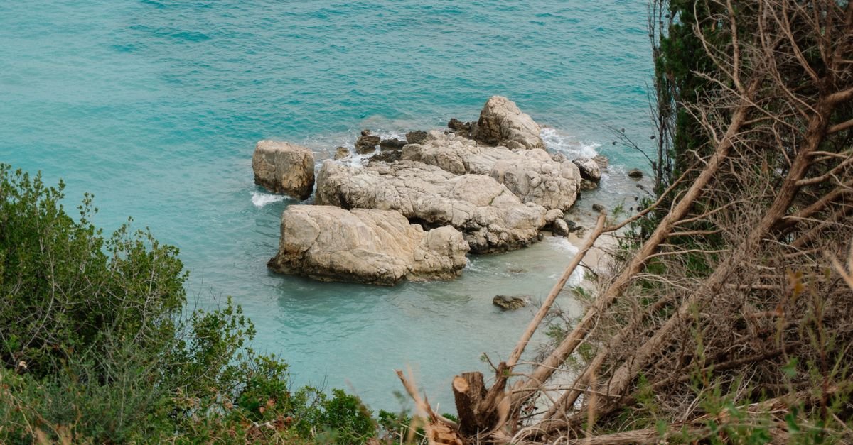 A clear-water cove with rocks and pale shingle