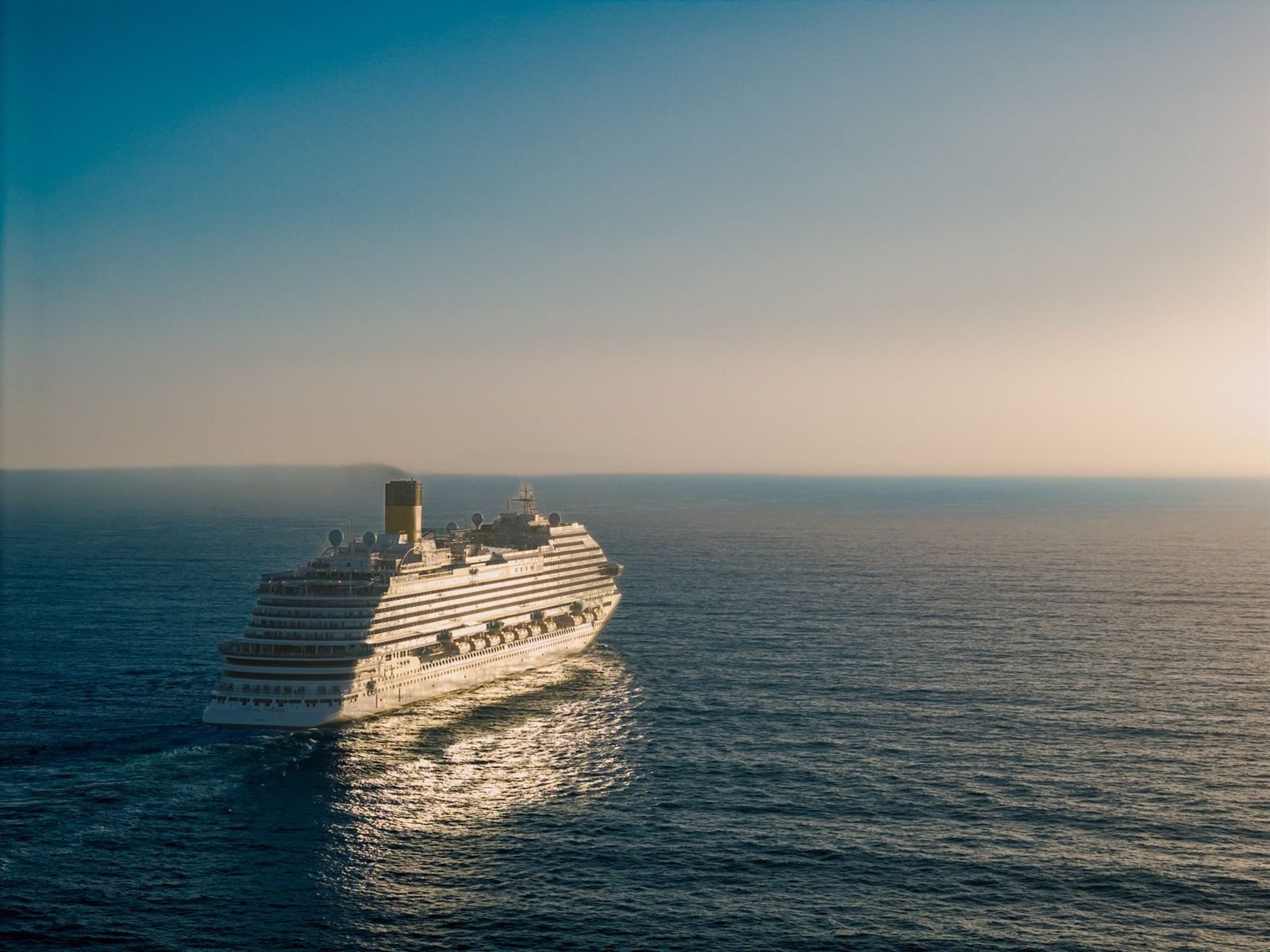 A large cruise ship on open water under a hazy horizon